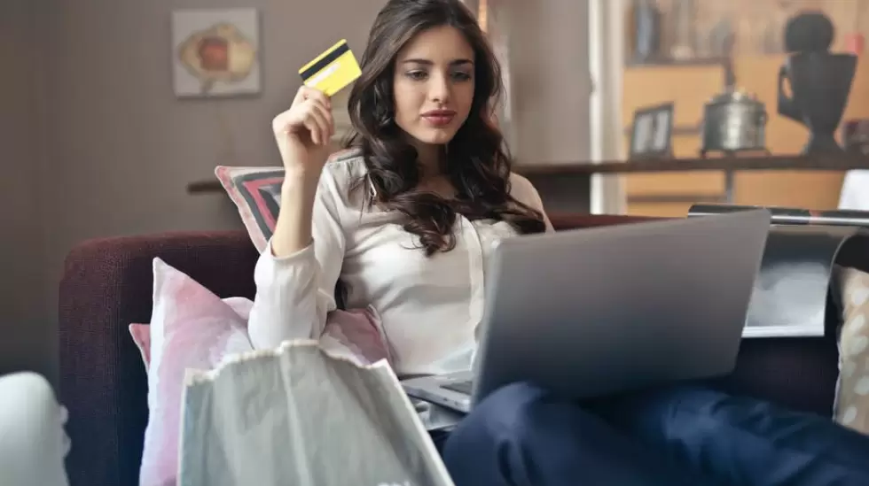 Mujer Sosteniendo Una Tarjeta Mientras Opera Un Porttil Plateado