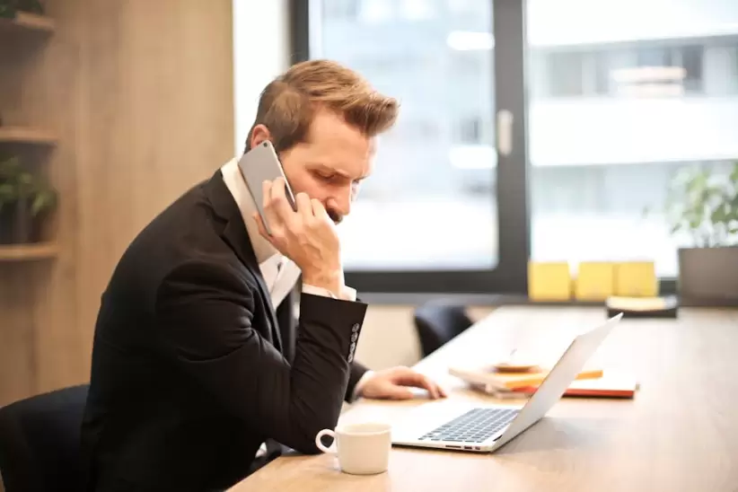 Hombre Que Tiene Una Llamada Telefónica Frente A Una Computadora Portátil