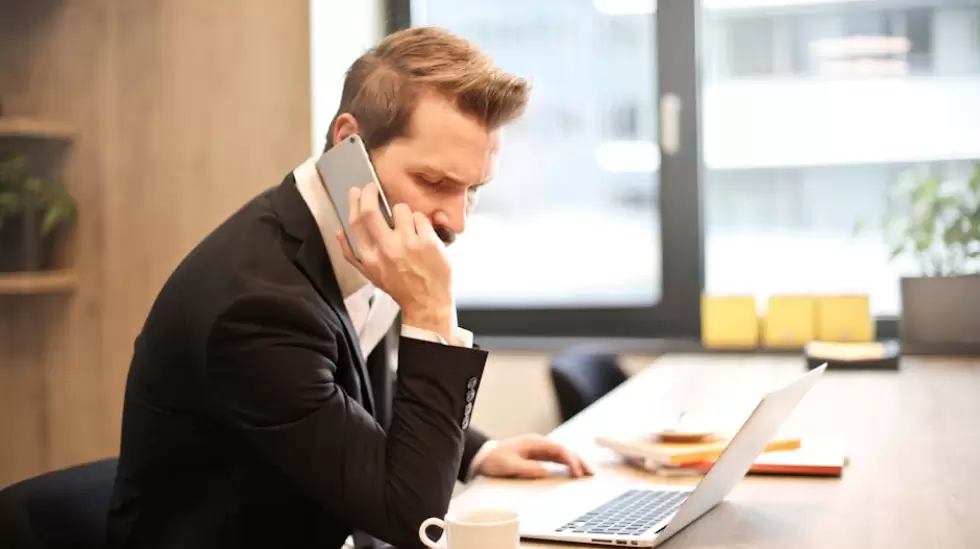 Hombre Que Tiene Una Llamada Telefnica Frente A Una Computadora Porttil