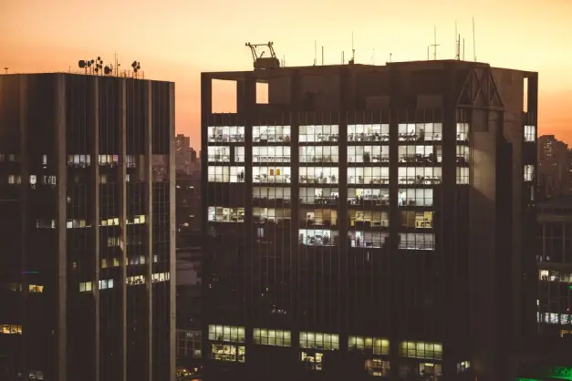 Edificios de oficinas de la ciudad iluminados contra un fondo de atardecer, mostrando la vida urbana. (Foto: Pexels)