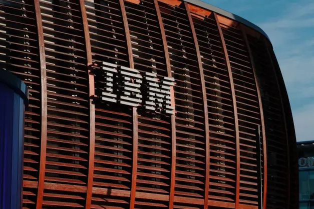 Primer plano del logotipo de IBM en una fachada arquitectónica moderna bajo un cielo azul claro. (Foto: Pexels)