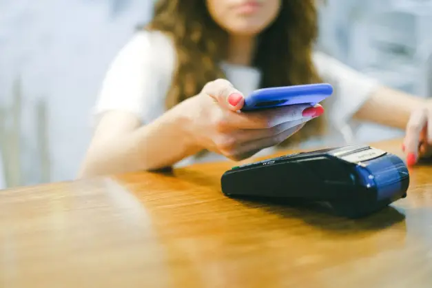 Una mujer realiza un pago sin contacto utilizando su smartphone en un terminal de pago. (Foto: Pexels)