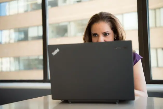 Mujer concentrada usando un portátil en un entorno de oficina bien iluminado, mostrando tecnología laboral moderna. (Foto: Pexels)