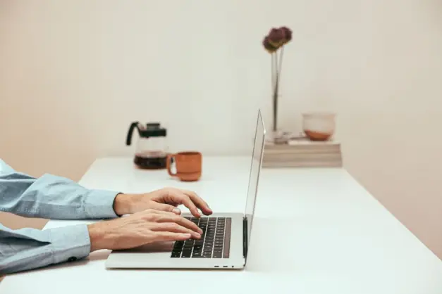 Manos tecleando en un portátil en una oficina moderna en casa, simbolizando el estilo de vida del trabajo remoto contemporáneo. (Foto: Pexels)