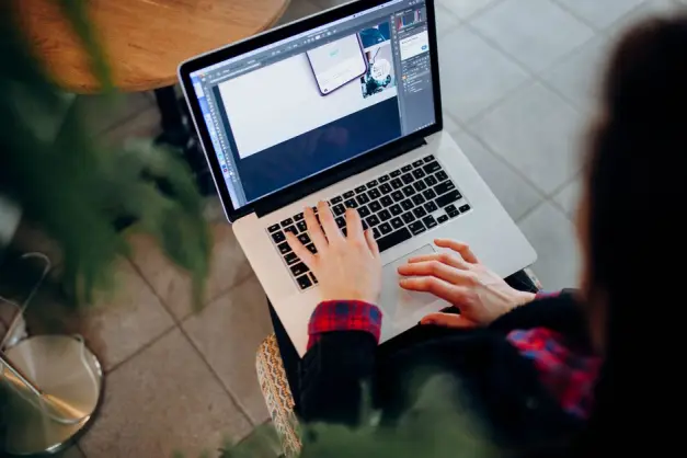 Toma en ángulo alto de una persona usando un portátil con software de diseño, en interiores sobre un suelo de baldosas. (Foto: Pexels)