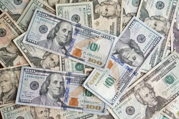 Un primer plano de billetes de dólar estadounidense esparcidos que muestran varias denominaciones y presidentes.