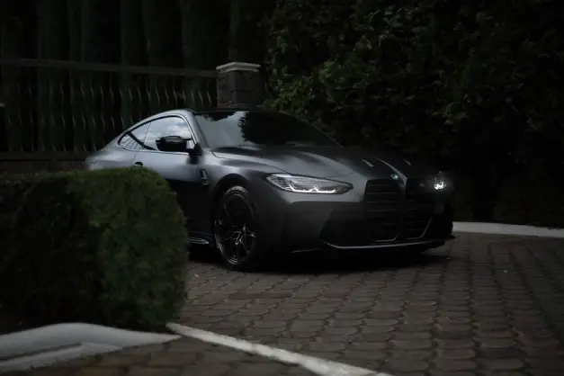 Coche deportivo negro aparcado al aire libre sobre una superficie pavimentada con vegetación alrededor. (Foto: Pexels)