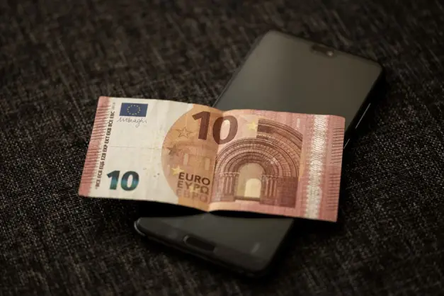 Una toma en primer plano de un billete de 10 euros colocado sobre un smartphone, destacando la moneda y la tecnología digital. (Foto: Pexels)