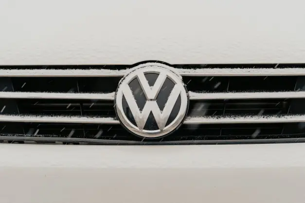 Primer plano de una parrilla de coche Volkswagen cubierto de nieve que muestra el icónico logo de VW. (Foto: Pexels)