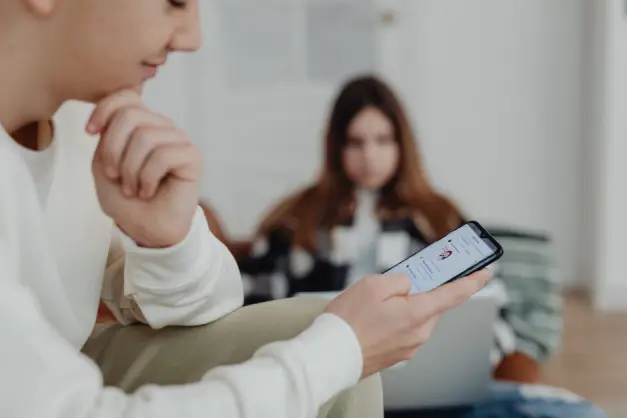 Adolescentes usando smartphones en interiores con un fondo borroso, sugiriendo interacción en redes sociales. (Foto: Pexels)