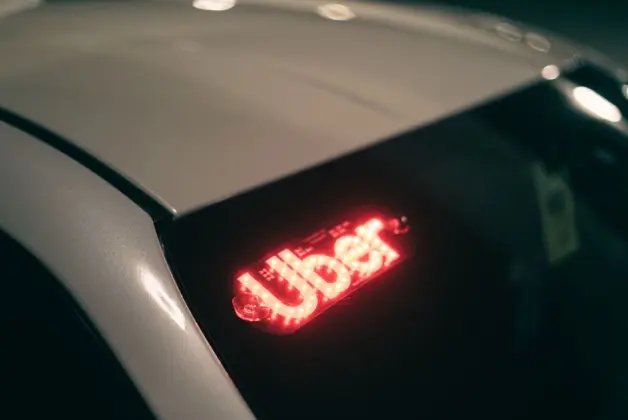 Primer plano de un coche de ridesharing con un letrero iluminado en rojo para viajes nocturnos. (Foto: Pexels)