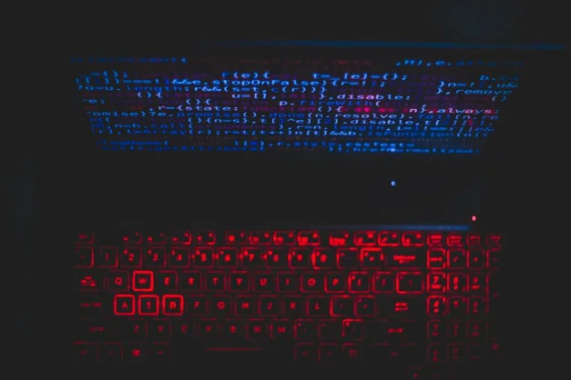 Configuración de laptop de temática oscura con teclado rojo iluminado y código en la pantalla, ideal para entusiastas de la tecnología.