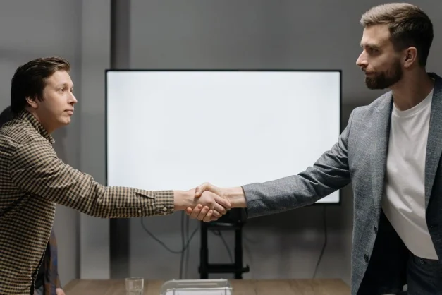 Dos hombres de negocios se dan la mano en un entorno de oficina, significando acuerdo y cooperación.
