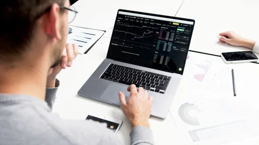 Profesional de negocios analizando datos del mercado de valores en un portátil para obtener ideas de inversión.