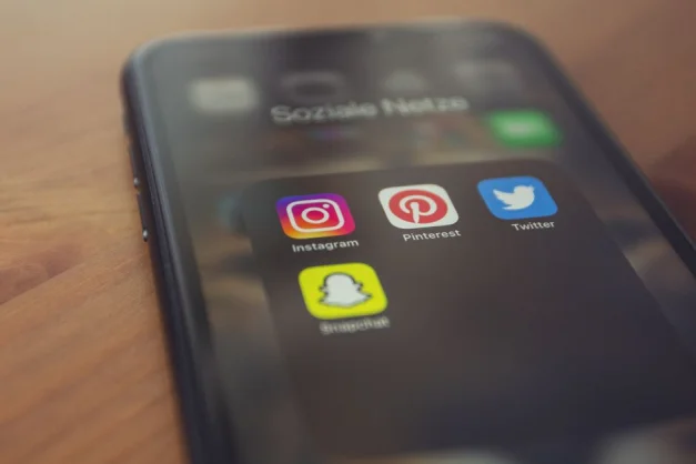 Smartphone mostrando aplicaciones populares de redes sociales como Instagram, Pinterest, Twitter y Snapchat.