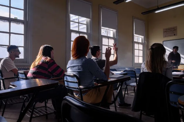 Los alumnos escuchan atentamente y participan en un debate en clase.
