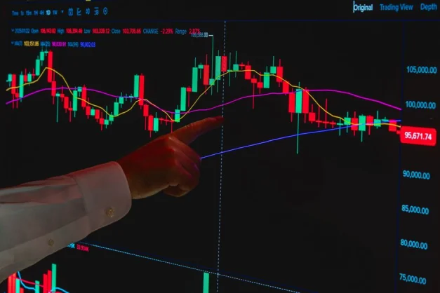 Una mano señala un gráfico bursátil en una pantalla digital, simbolizando el análisis financiero.