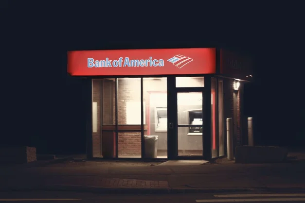 Estructura iluminada del cajero automático de Bank of America contra un fondo oscuro nocturno en Boston.