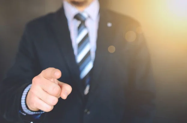 Hombre de negocios seguro en traje apuntando hacia adelante, simbolizando liderazgo y enfoque.
